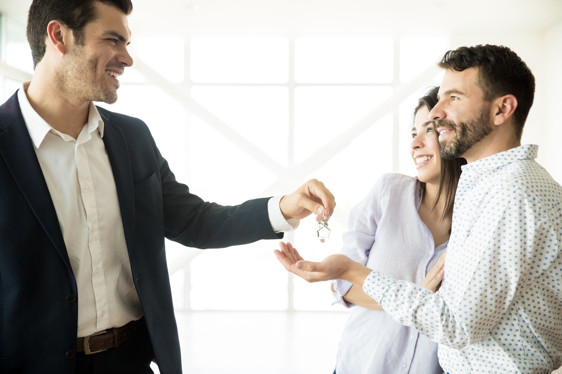 Three coworkers smiling and exchanging a handshake in a bright office