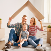 Family exiting a brick house. A child runs ahead while parents follow smiling.
