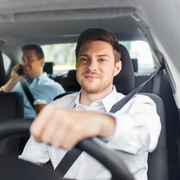 Man driving car with two children. Sunlight, smiles, seatbelts.