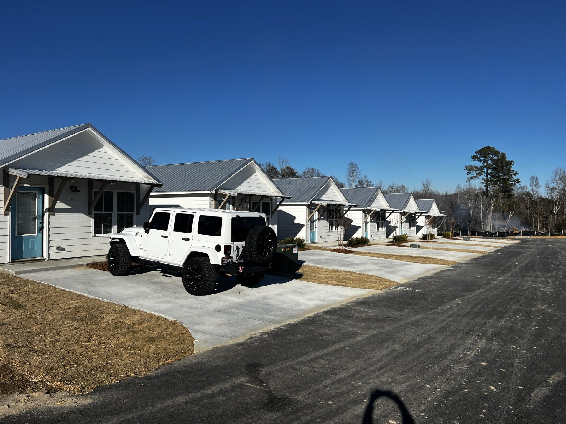 A white jeep is parked in front of a row of houses A white jeep is parked in front of a row of houses
