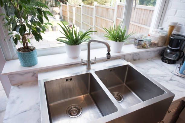 A kitchen sink is sitting on a counter next to a window- Luther Falls Kitchen & Bath - Champaign, IL