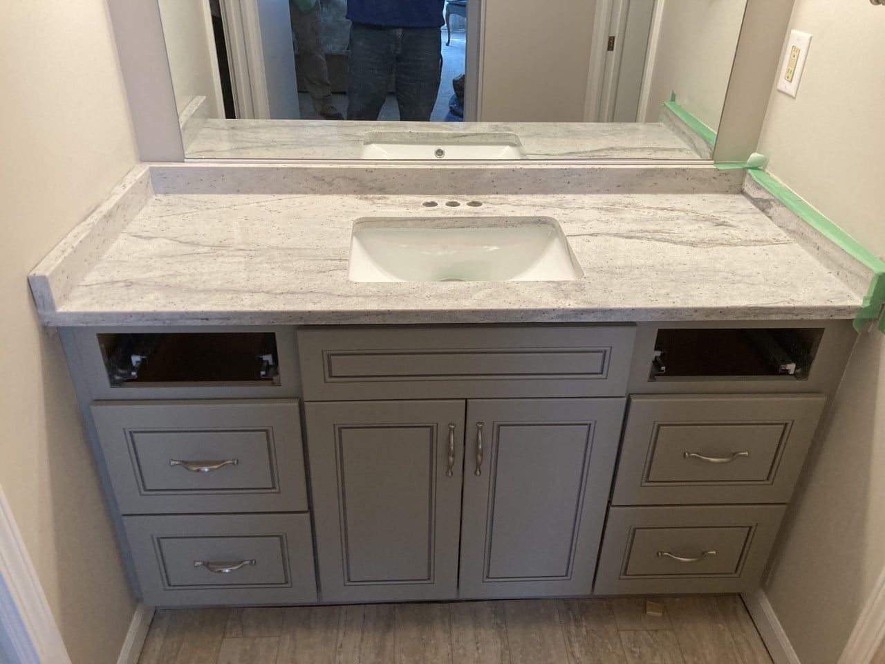 A bathroom vanity with a sink and a mirror - Luther Falls Kitchen & Bath - Champaign, IL