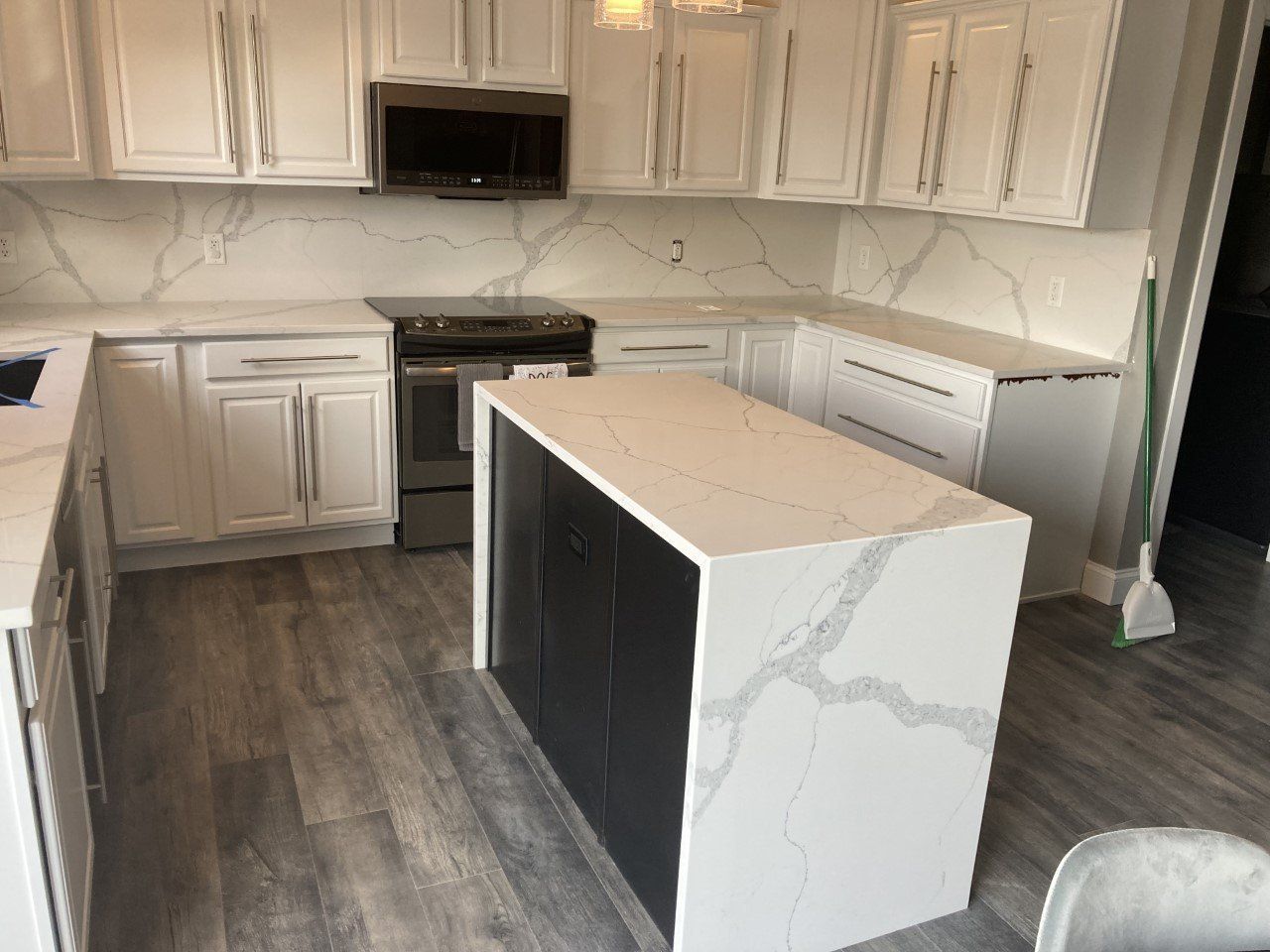 A kitchen with white cabinets and a large island in the middle - Luther Falls Kitchen & Bath - Champaign, IL