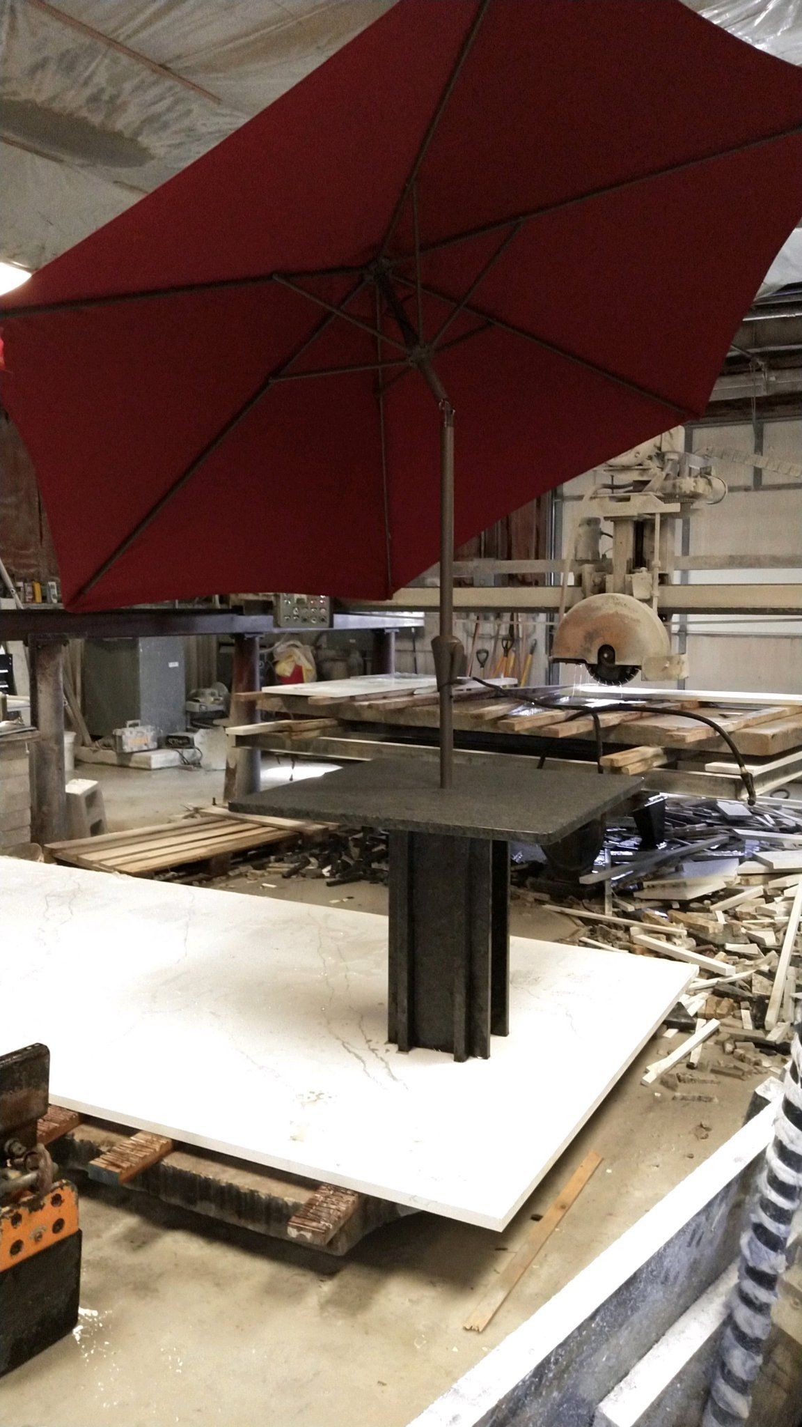 A red umbrella is sitting on top of a table in a warehouse - Luther Falls Kitchen & Bath - Champaign, IL