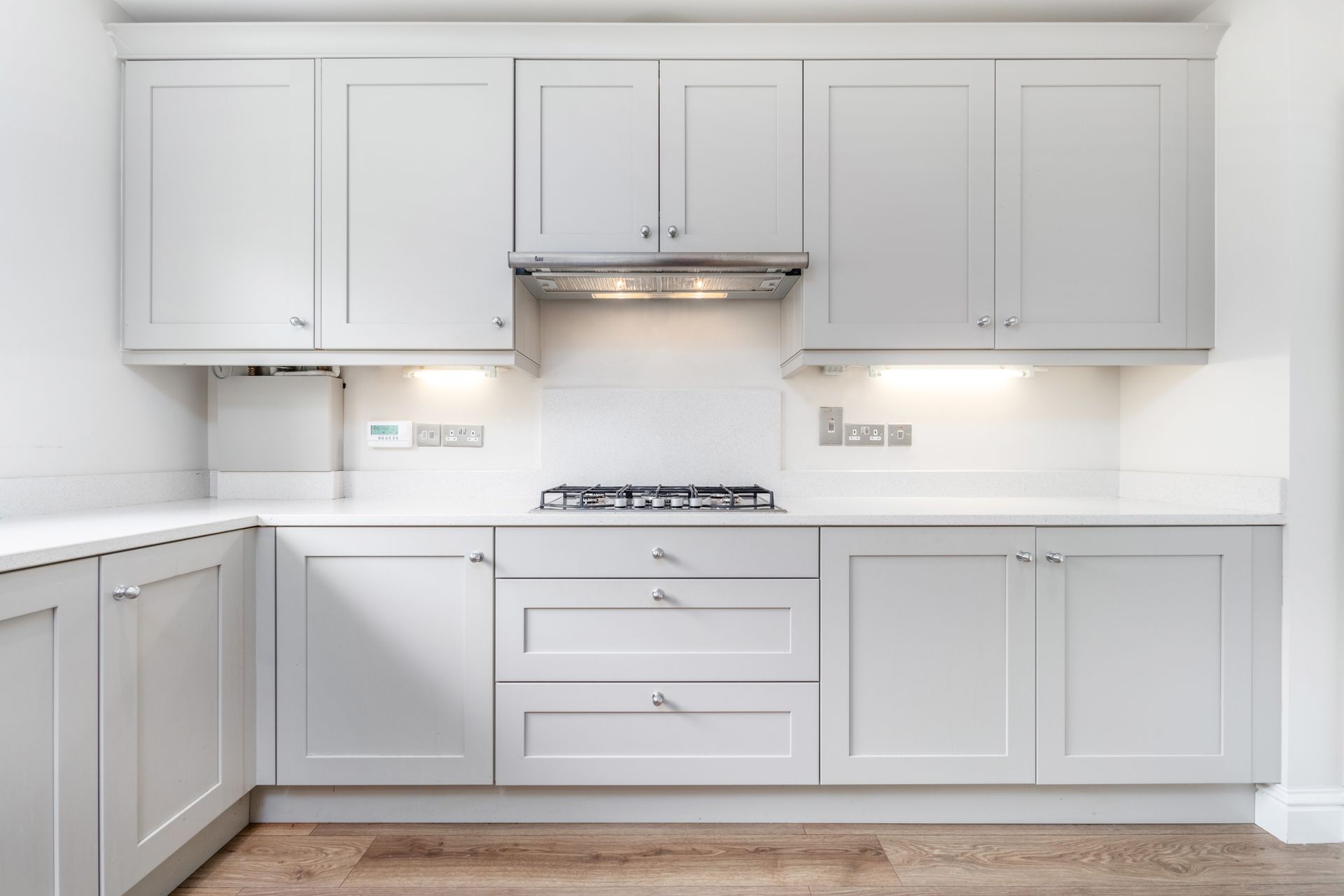 Modern kitchen with light gray cabinets, a gas stovetop, and white countertops.