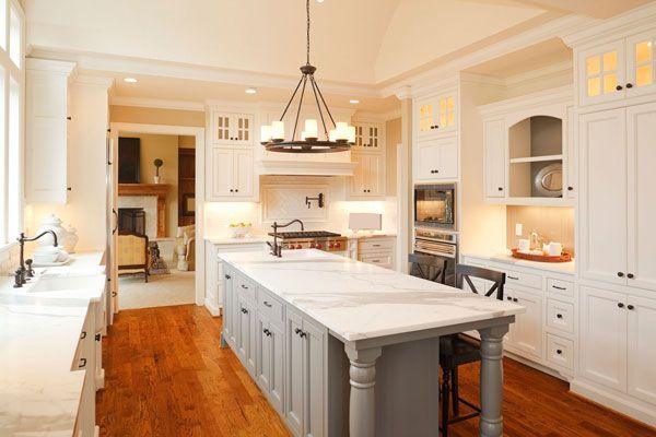 A modern kitchen with white cabinets, a large marble island, and stainless steel appliances. A modern kitchen with white cabinets, a large marble island, and stainless steel appliances.