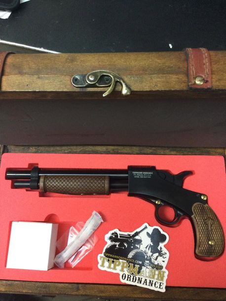 Toy revolver in an open case with stickers and small accessories on a red-lined background