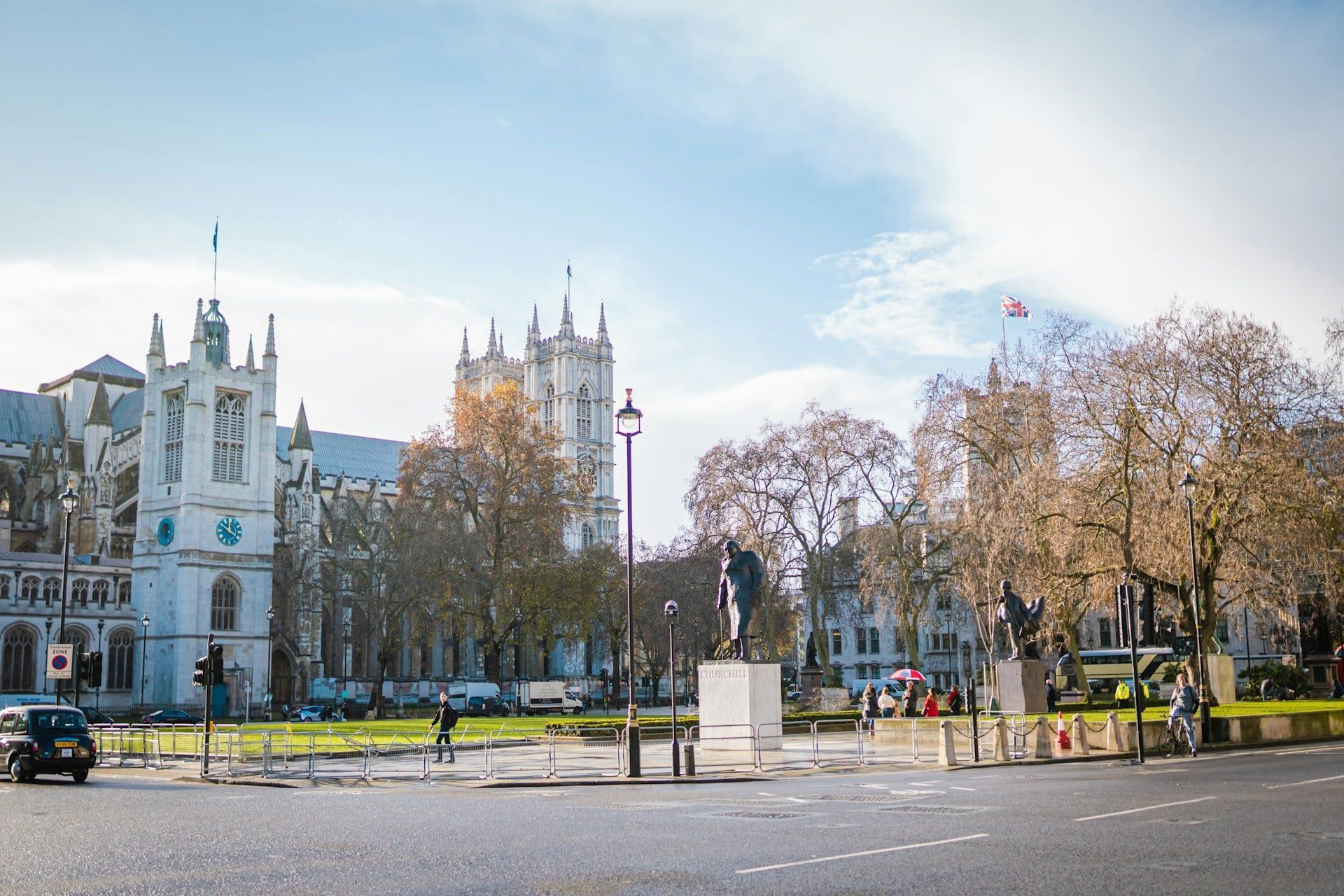 Historic building and trees in a bright town square under a clear blue sky