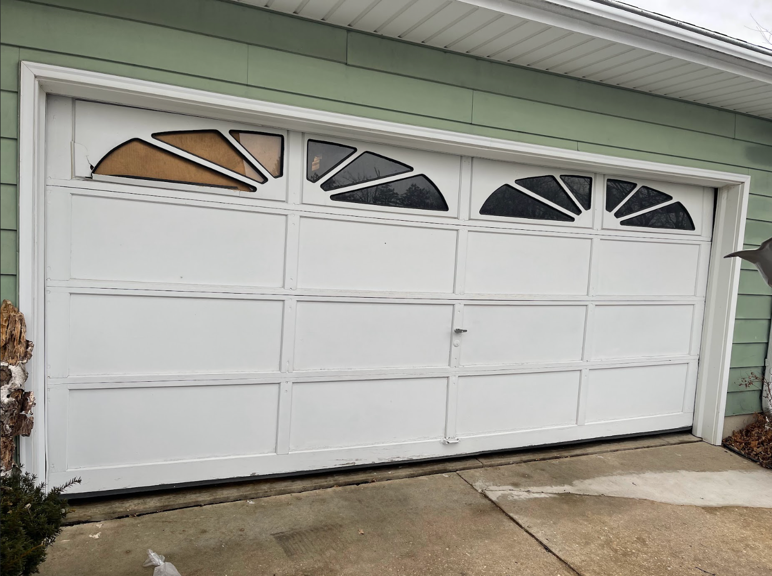A white garage door is sitting on the side of a house.