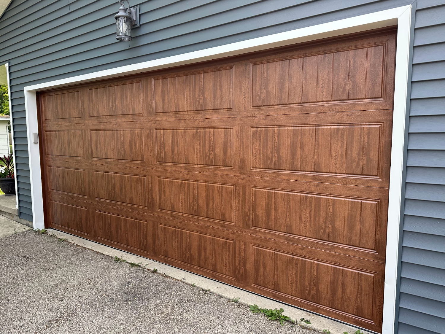A large wooden garage door is on the side of a house.