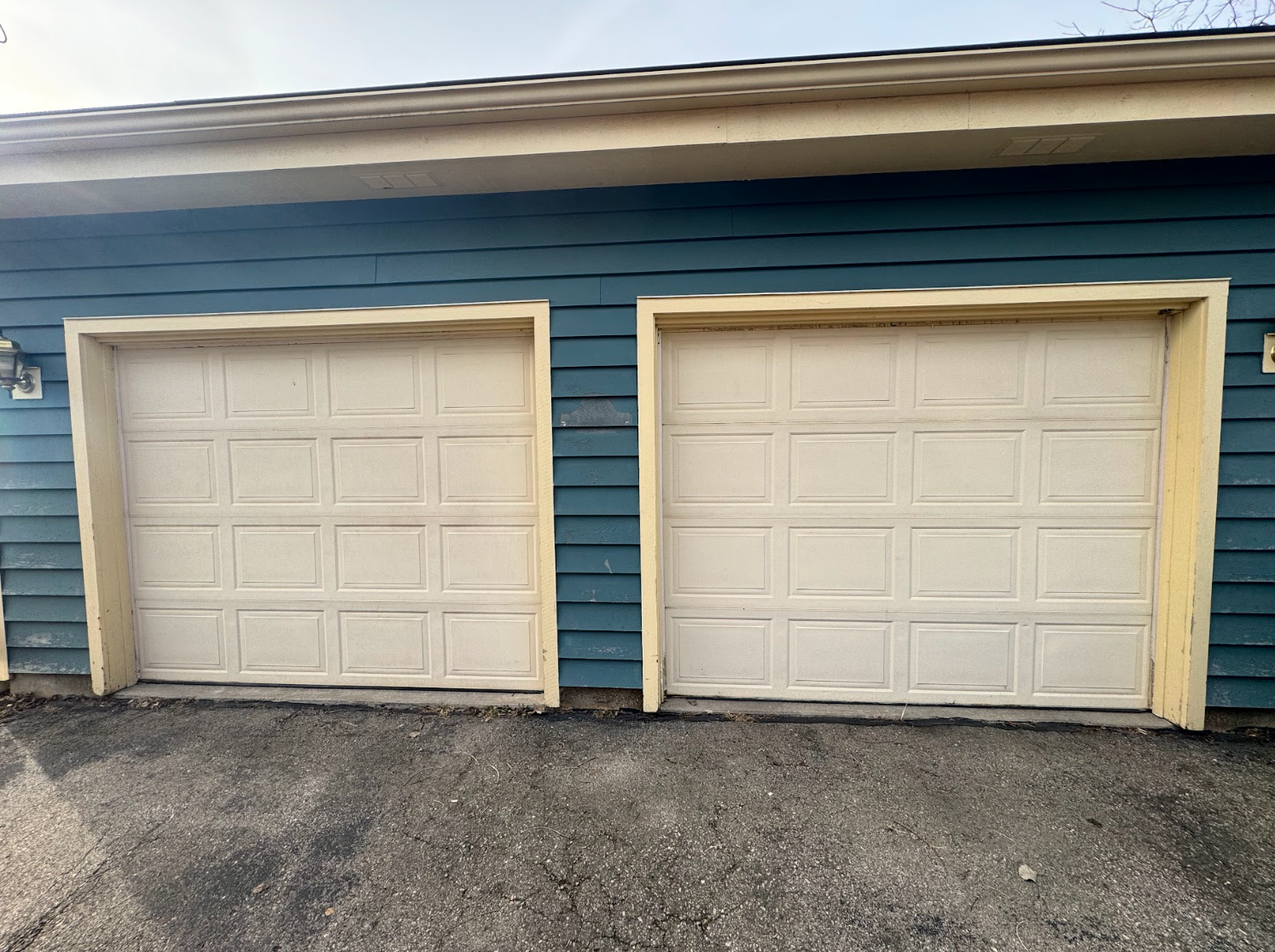There are two garage doors on the side of a house.