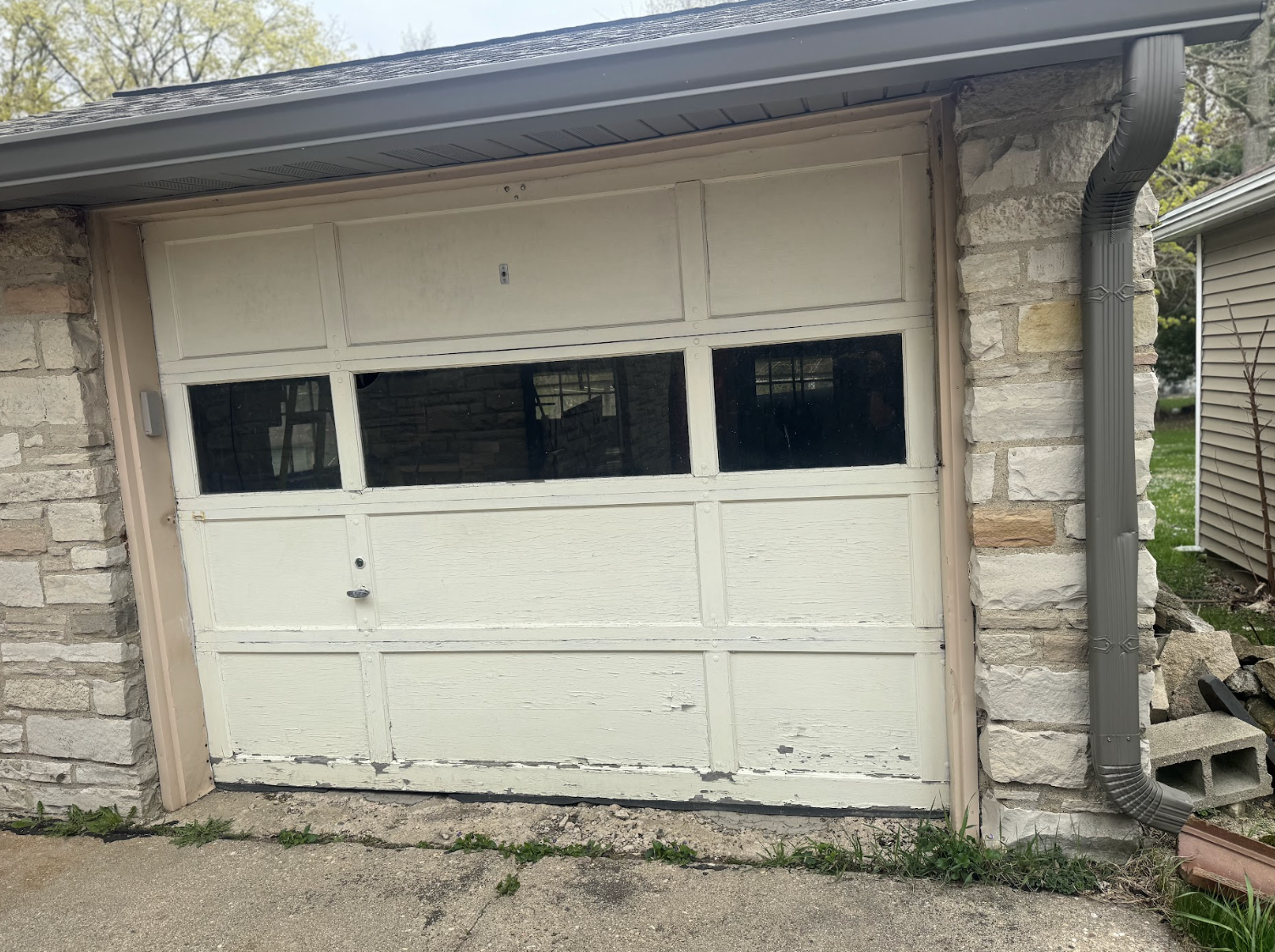 A white garage door is sitting in front of a stone building.