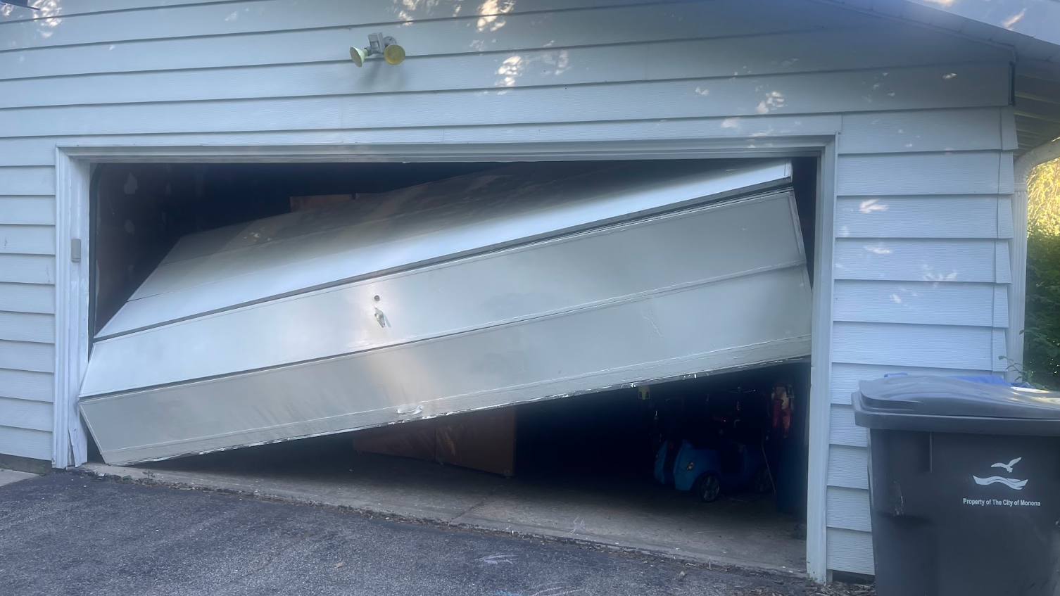 A garage door is open and a boat is sitting inside of it.