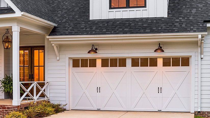A white house with a black roof and a white garage door.