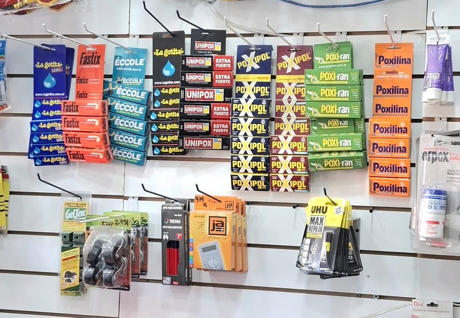 Surtido de accesorios y herramientas para automóviles empaquetados, expuestos en un estante de pared de la tienda.