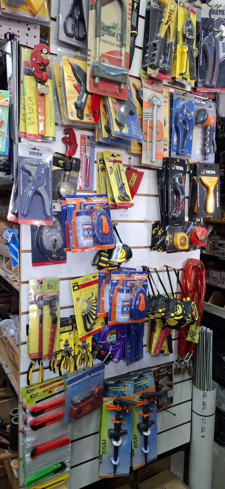 Diversas herramientas y artículos de ferretería colgados en un pasillo de la tienda, con coloridos envases.