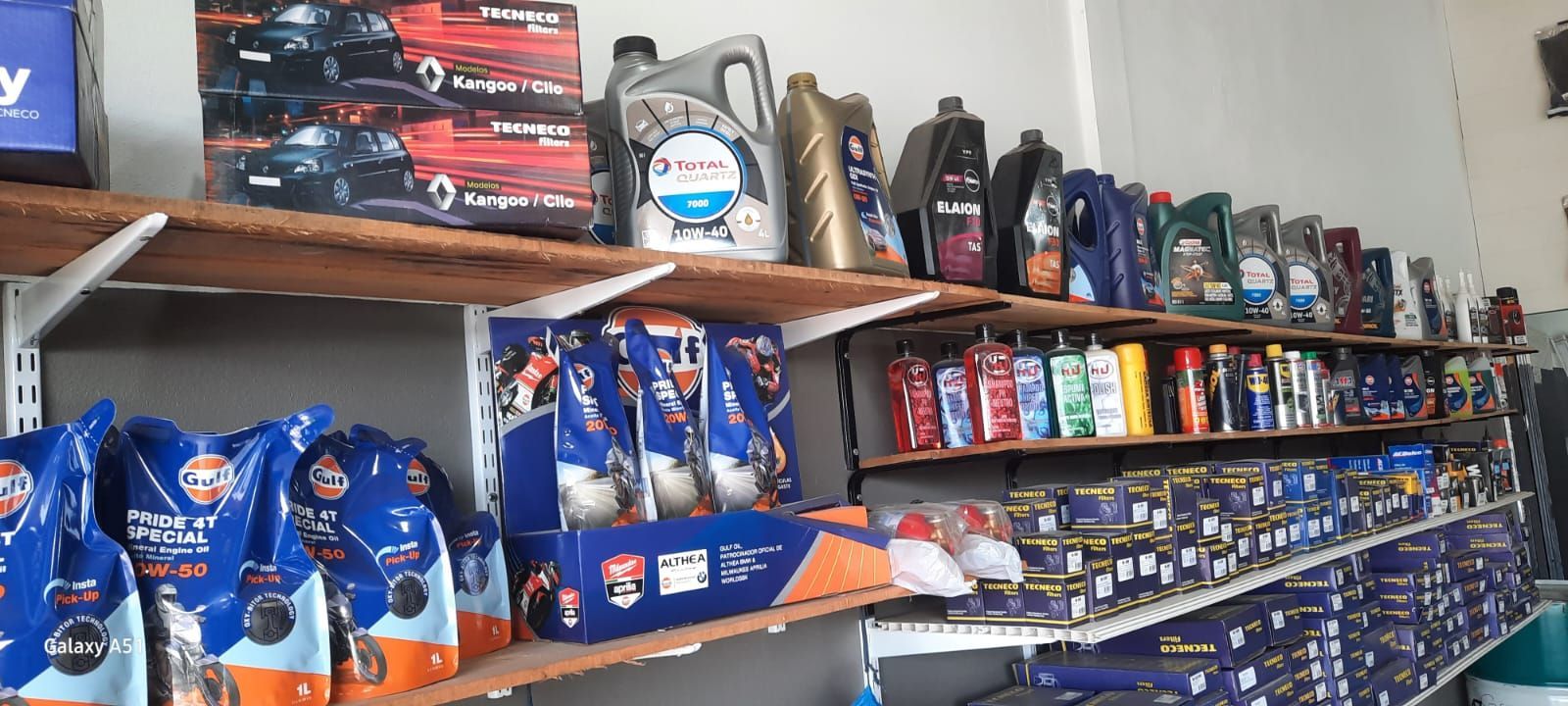 Estanterías repletas de aceites de motor y productos para el cuidado del automóvil en un pasillo de la tienda.
