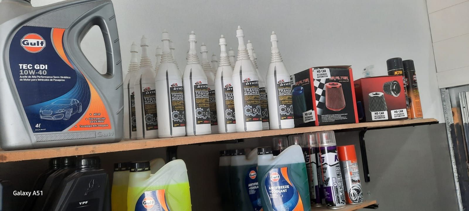 Estantería con productos para el cuidado del automóvil, incluyendo envases de aceite, botellas pulverizadoras y artículos de limpieza.