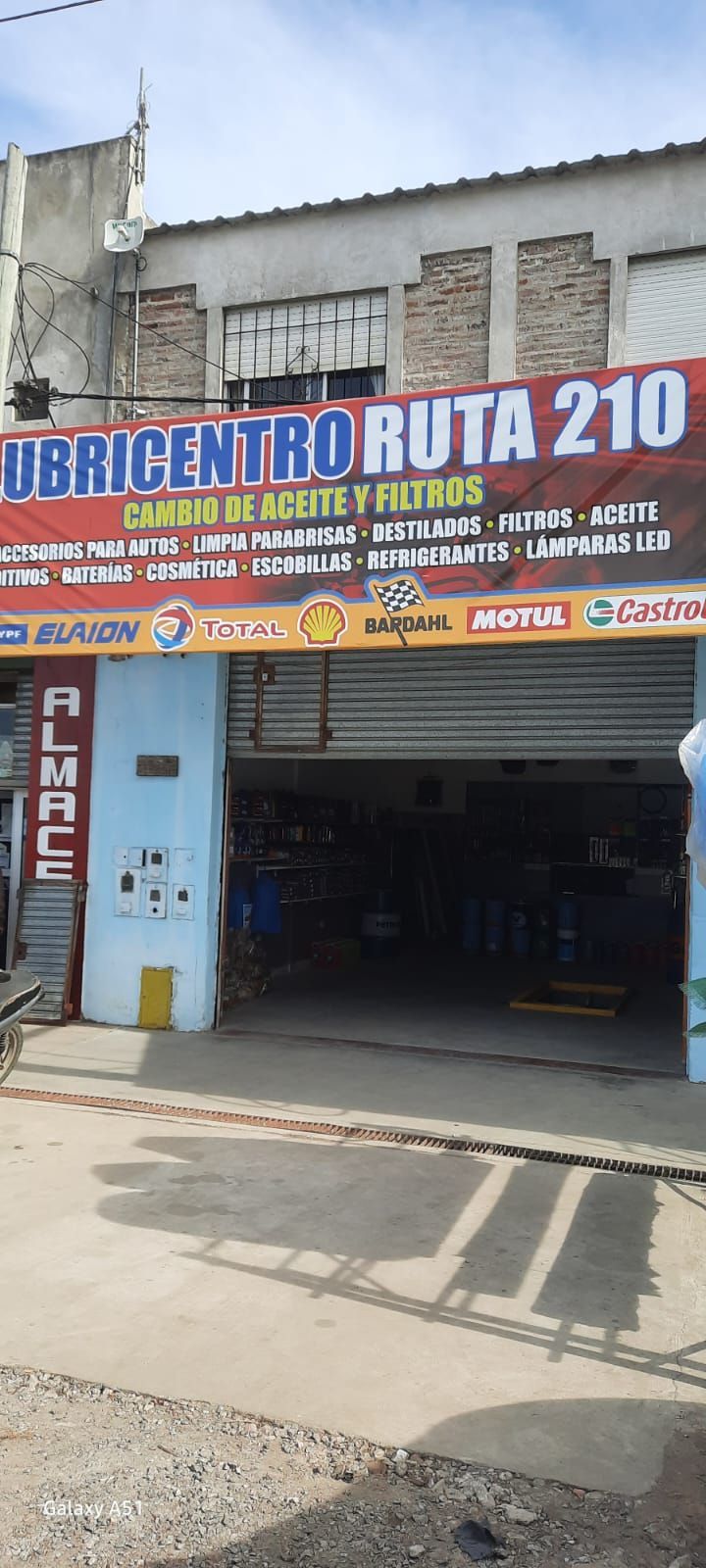 Local comercial con letrero azul y naranja que dice “UBICENTRO RUTA 210” sobre la entrada de un garaje.