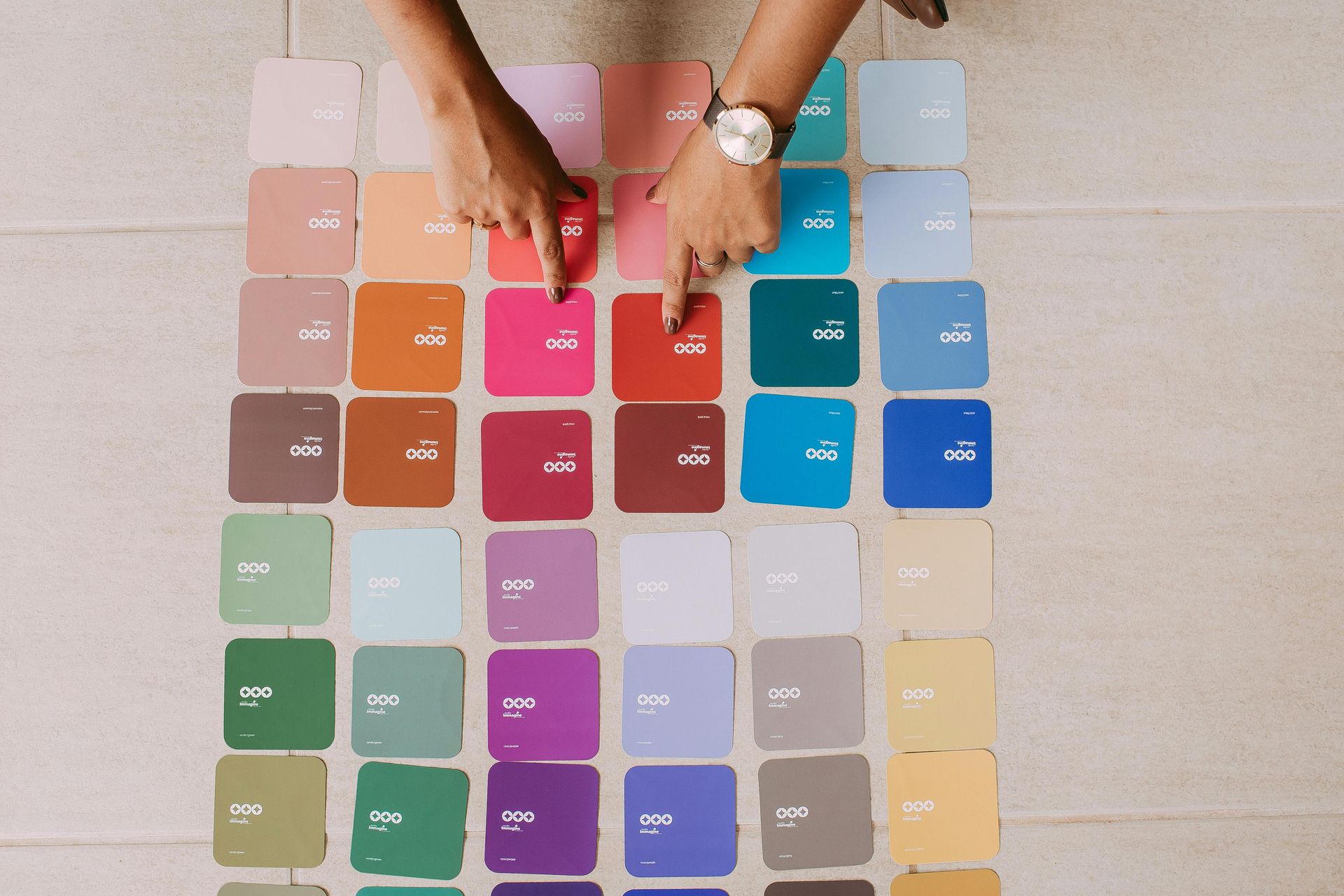 Hands arranging colorful swatches in a neat grid on a table