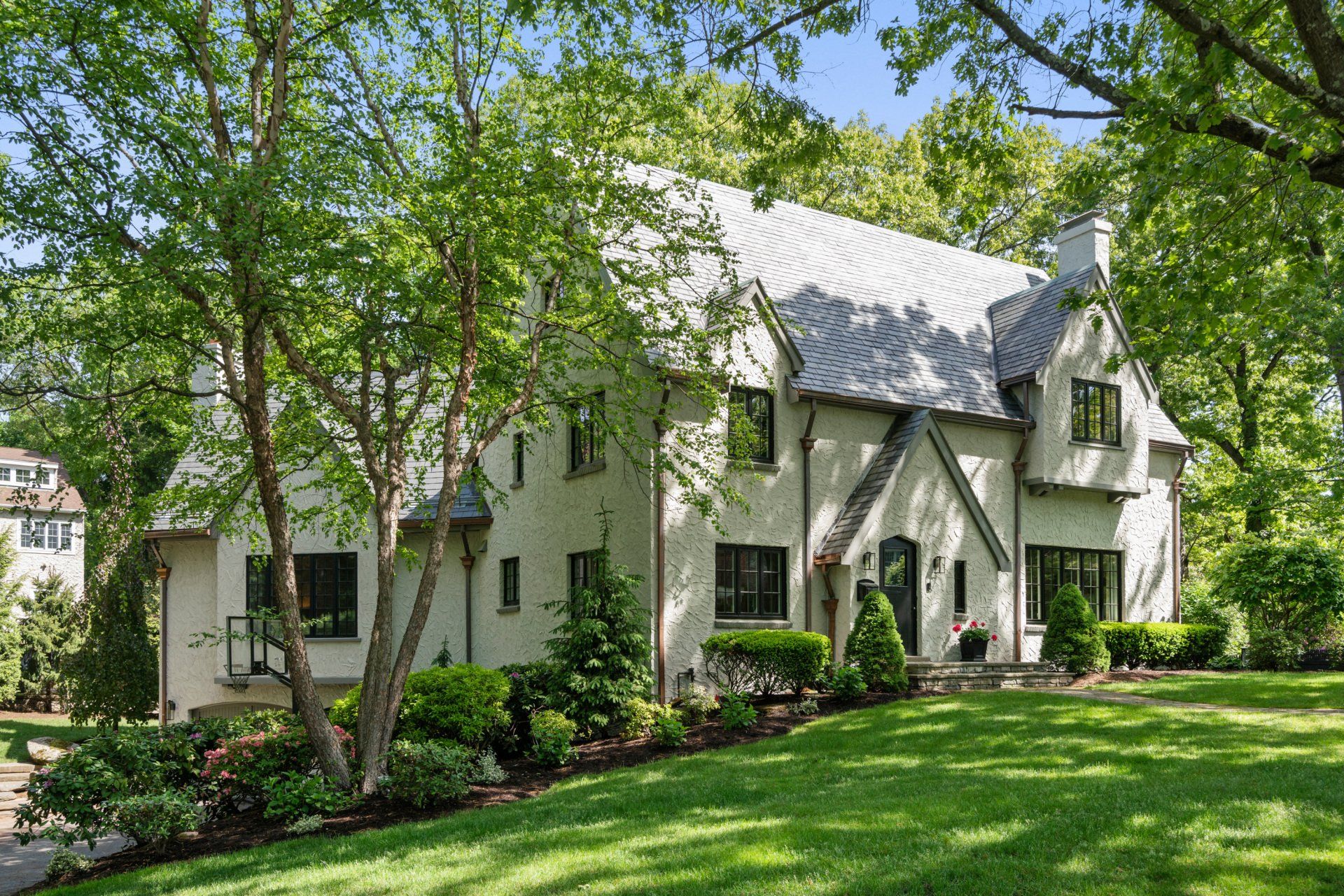 White house with gray roof and trees in a green lawn