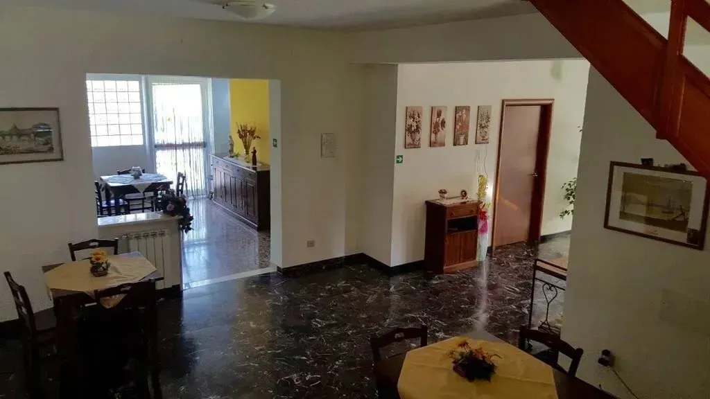 Spacious living room with dark tiled floor, staircase, dining table, and open doorway to a kitchen.