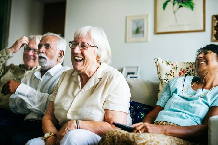 Three people smiling and laughing on a couch in a bright living room