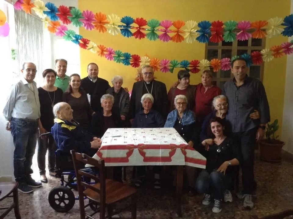 Group of people gathered around a decorated table in a festive room with colorful paper garlands
