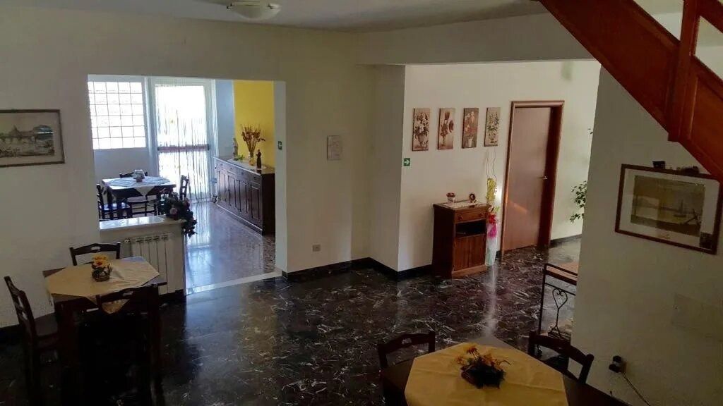 Living room with shiny black tile floor, staircase, tables, and a view into a bright dining area