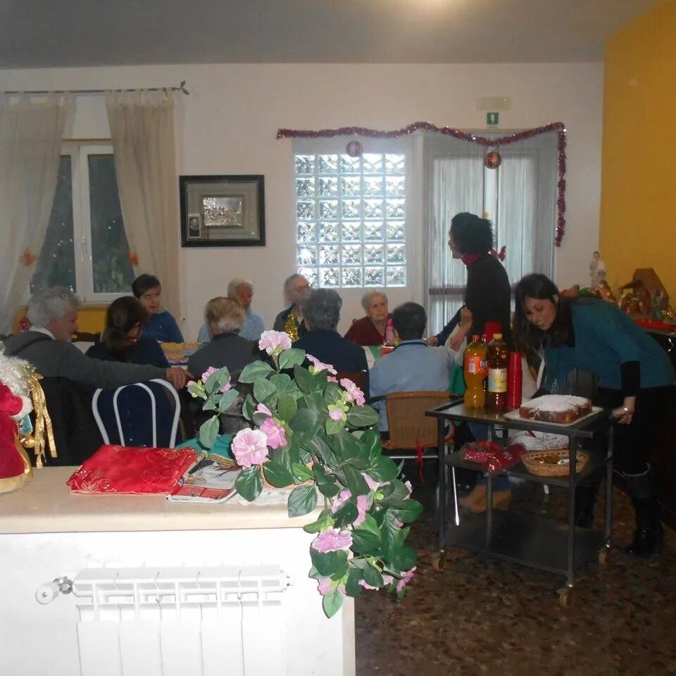 People seated around a table in a living room, with flowers, drinks, and holiday decorations.