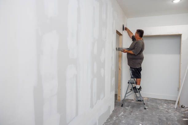 A man is standing on a ladder working on a wall. — New Windsor, NY — JJ Interior Restorations Corp.