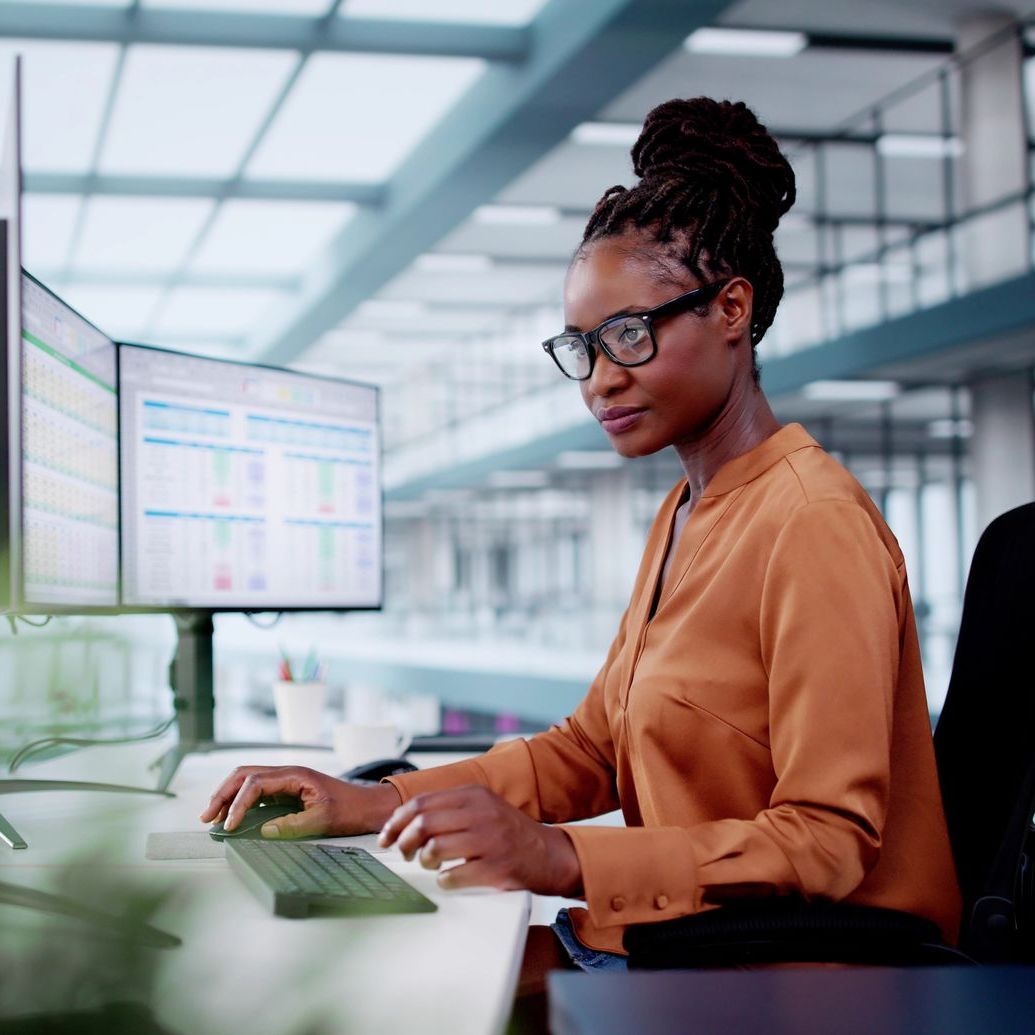 A woman is sitting at a desk in front of a computer.