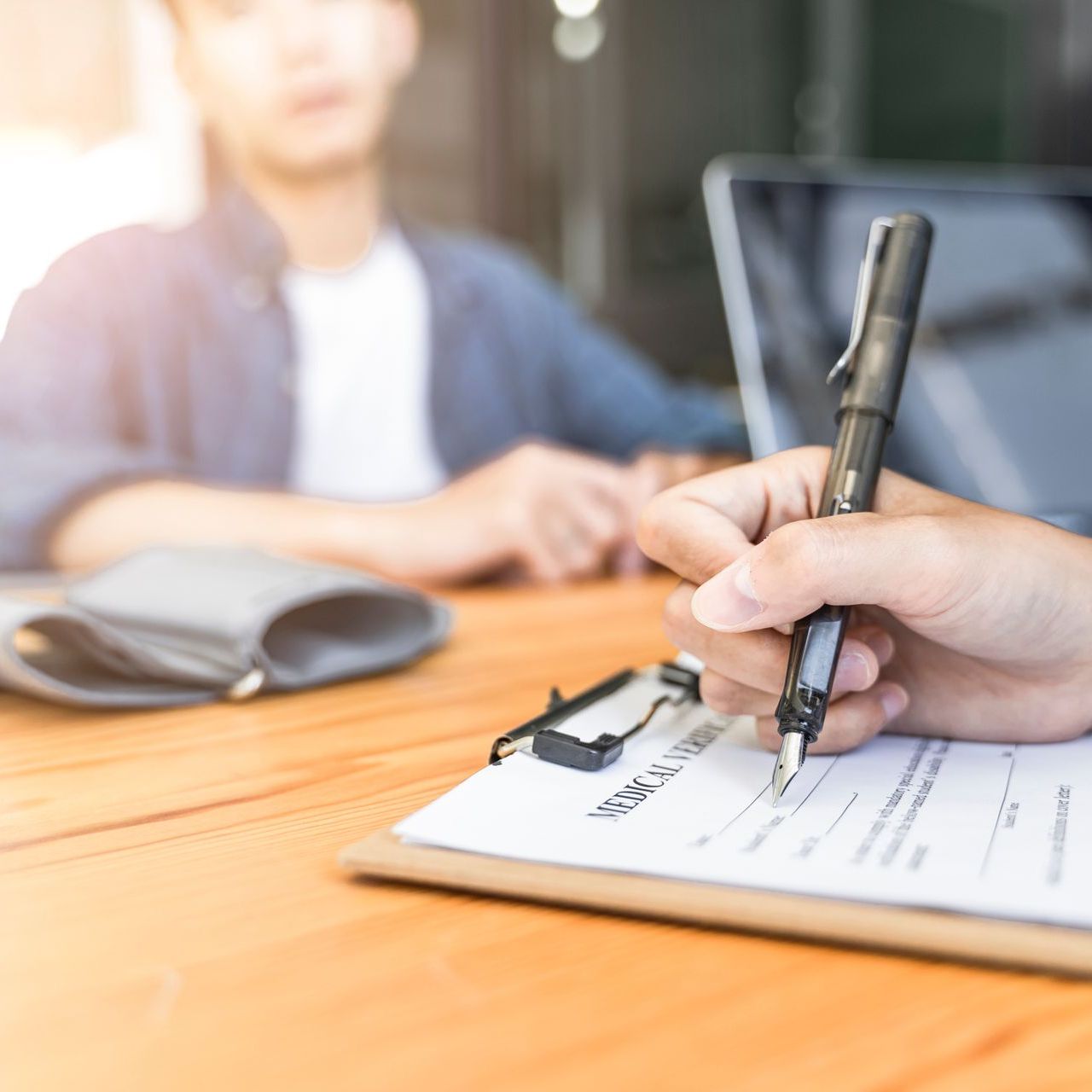 A doctor is writing on a clipboard while talking to a patient.