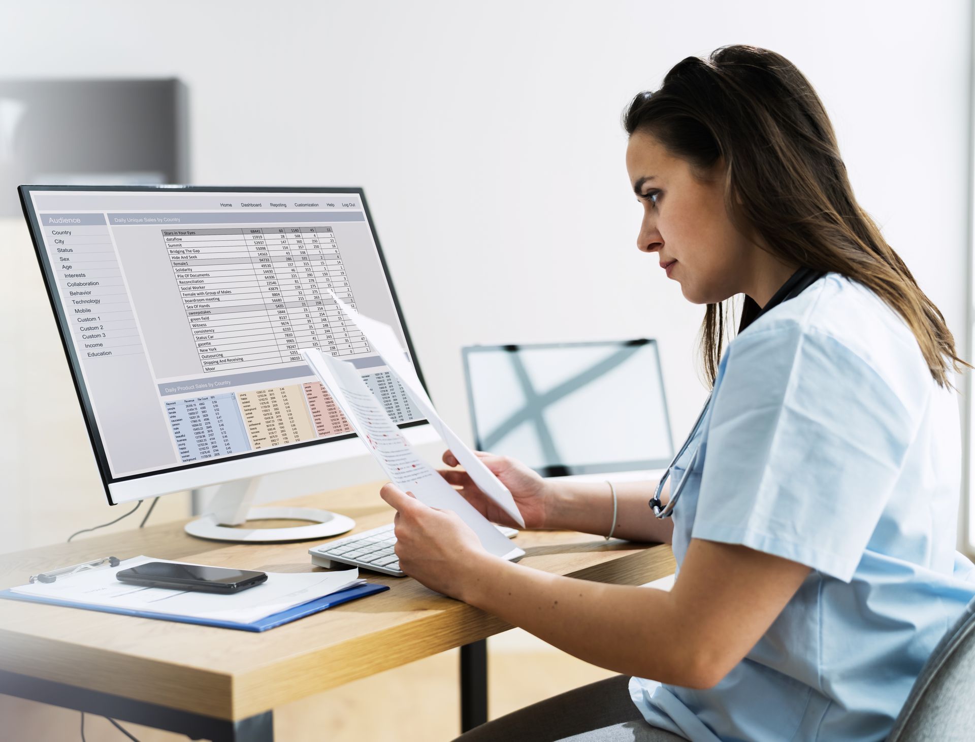 A nurse is sitting at a desk looking at a computer screen.