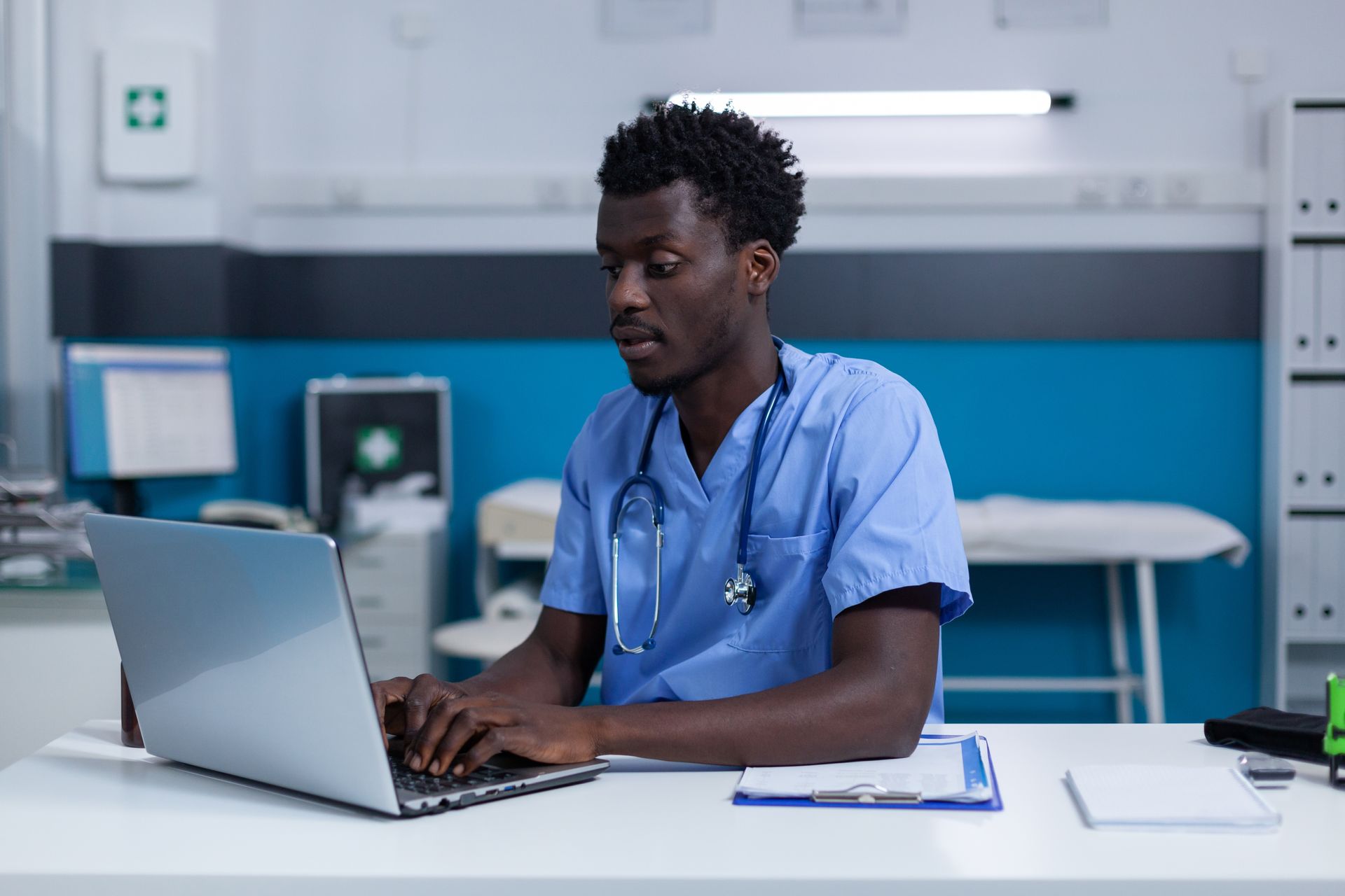 A doctor is sitting at a desk using a laptop computer.