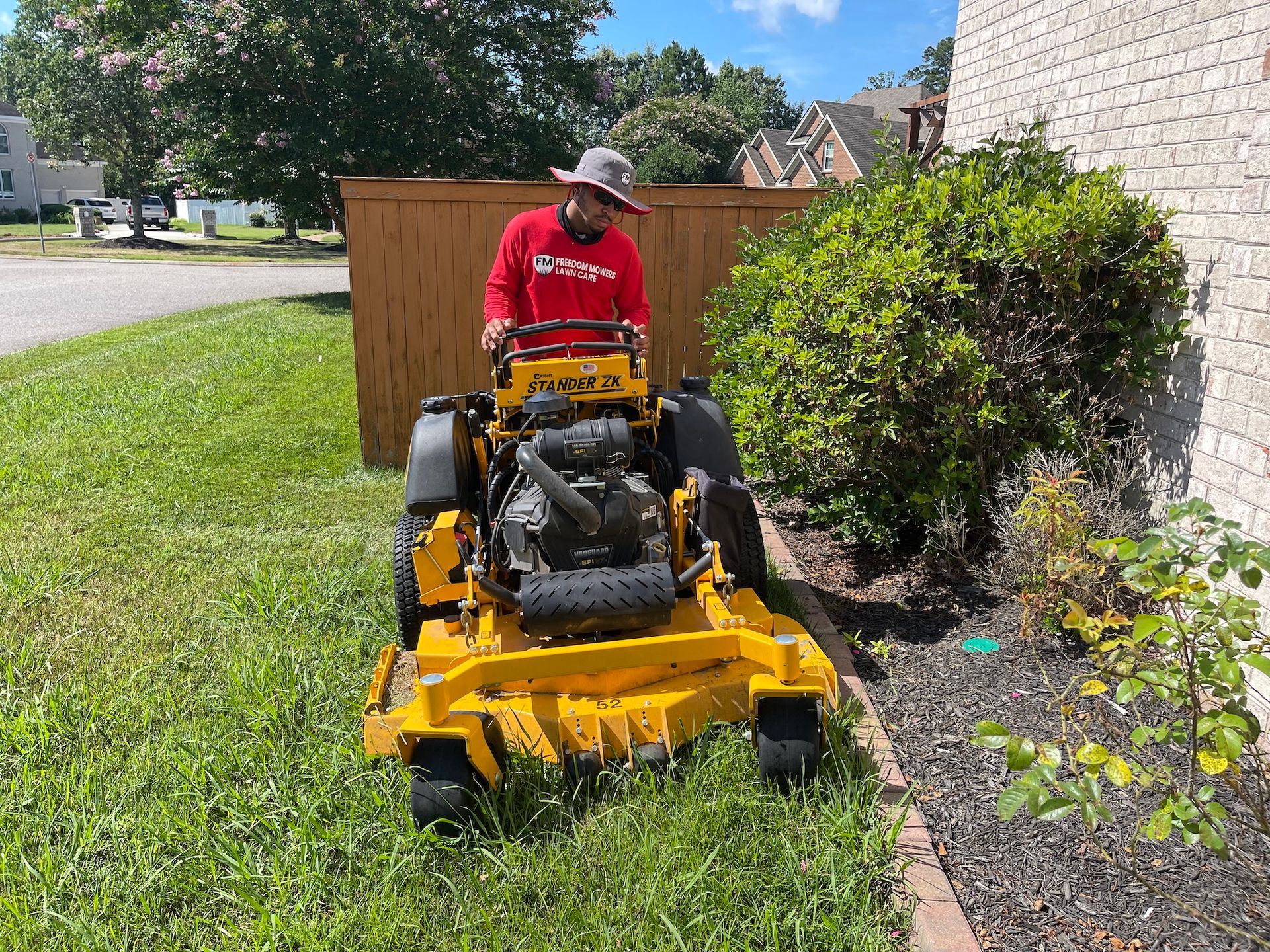 A man is riding a yellow lawn mower on a lush green lawn.