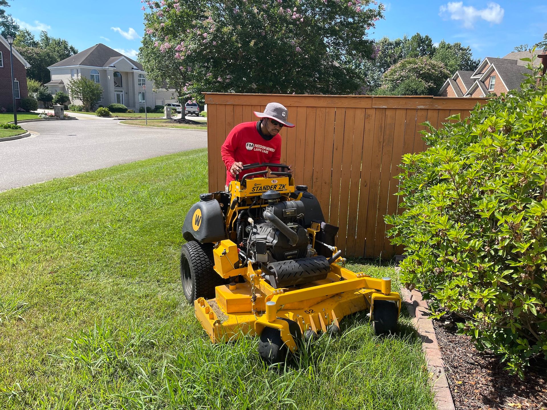 A man is riding a yellow lawn mower on a lush green lawn.