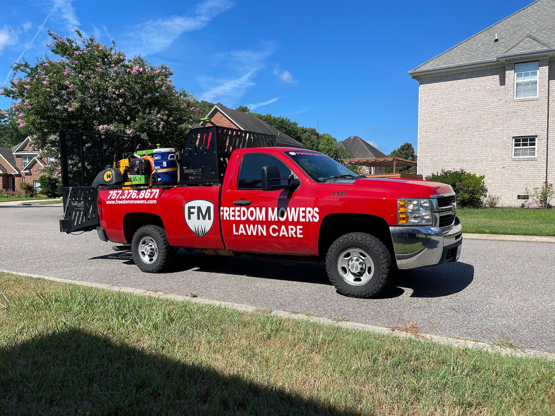 A red truck is parked on the side of the road in front of a house.