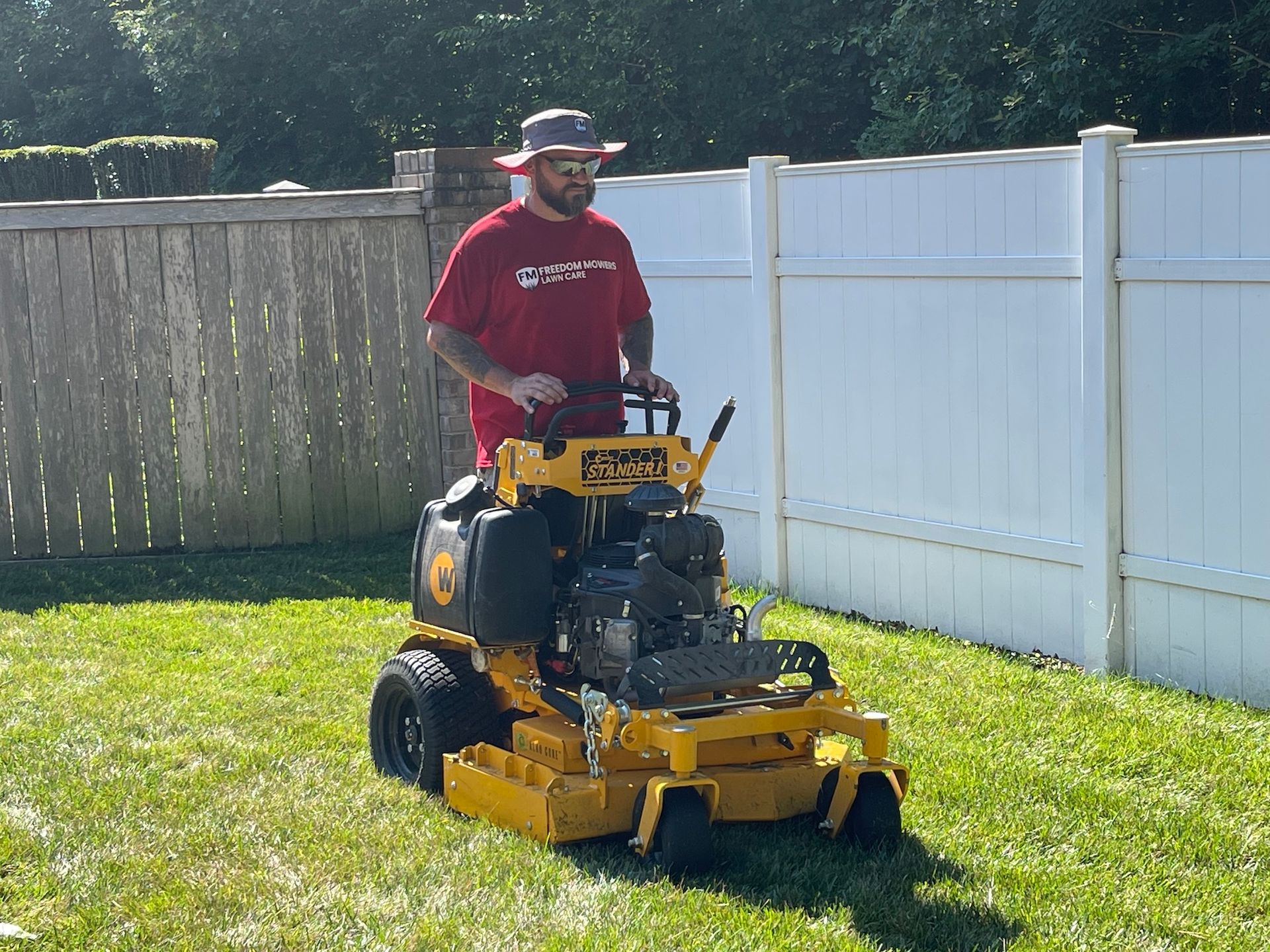 A man in a red shirt is riding a yellow lawn mower