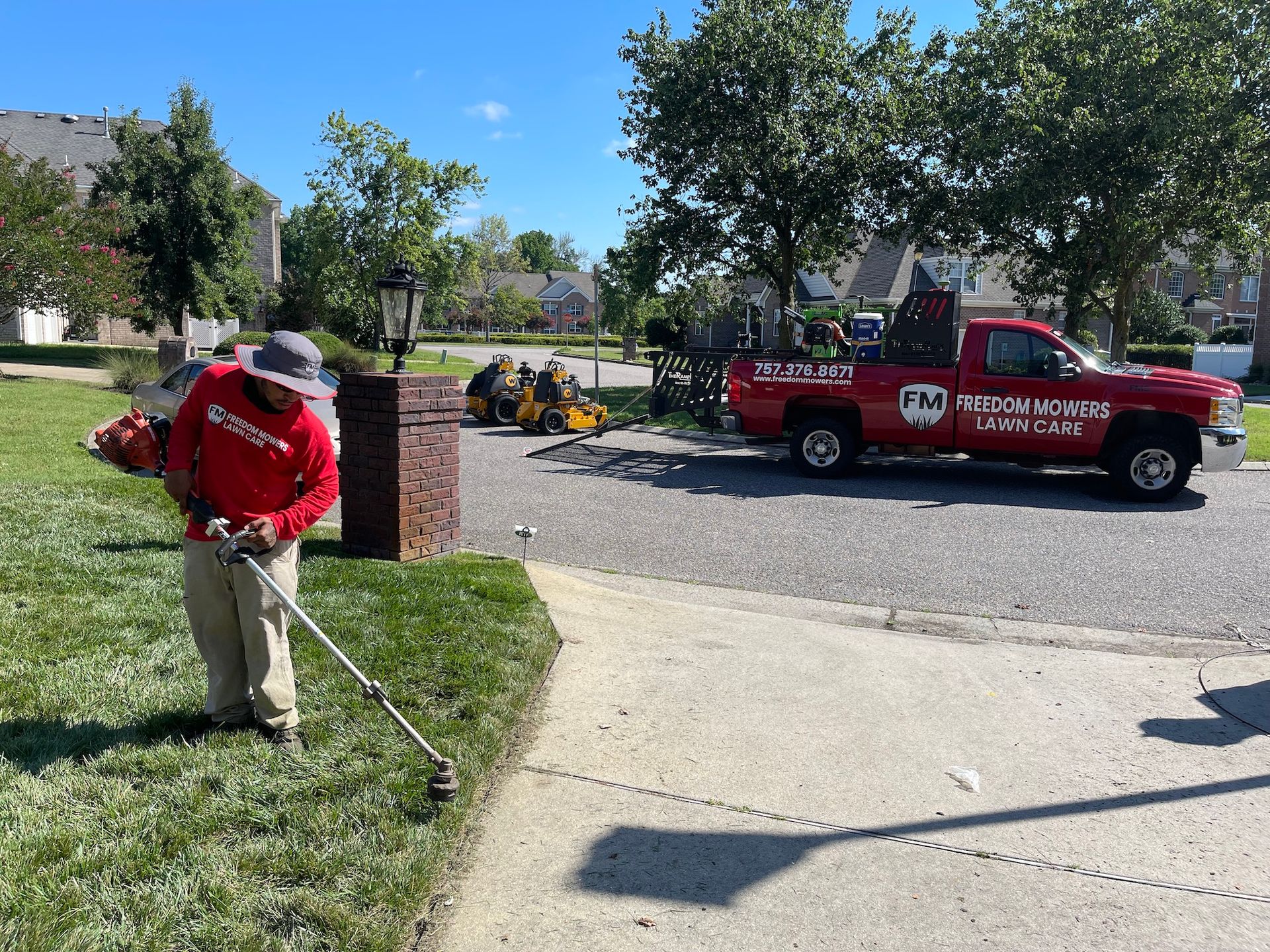 A man is mowing the grass in front of a red truck.