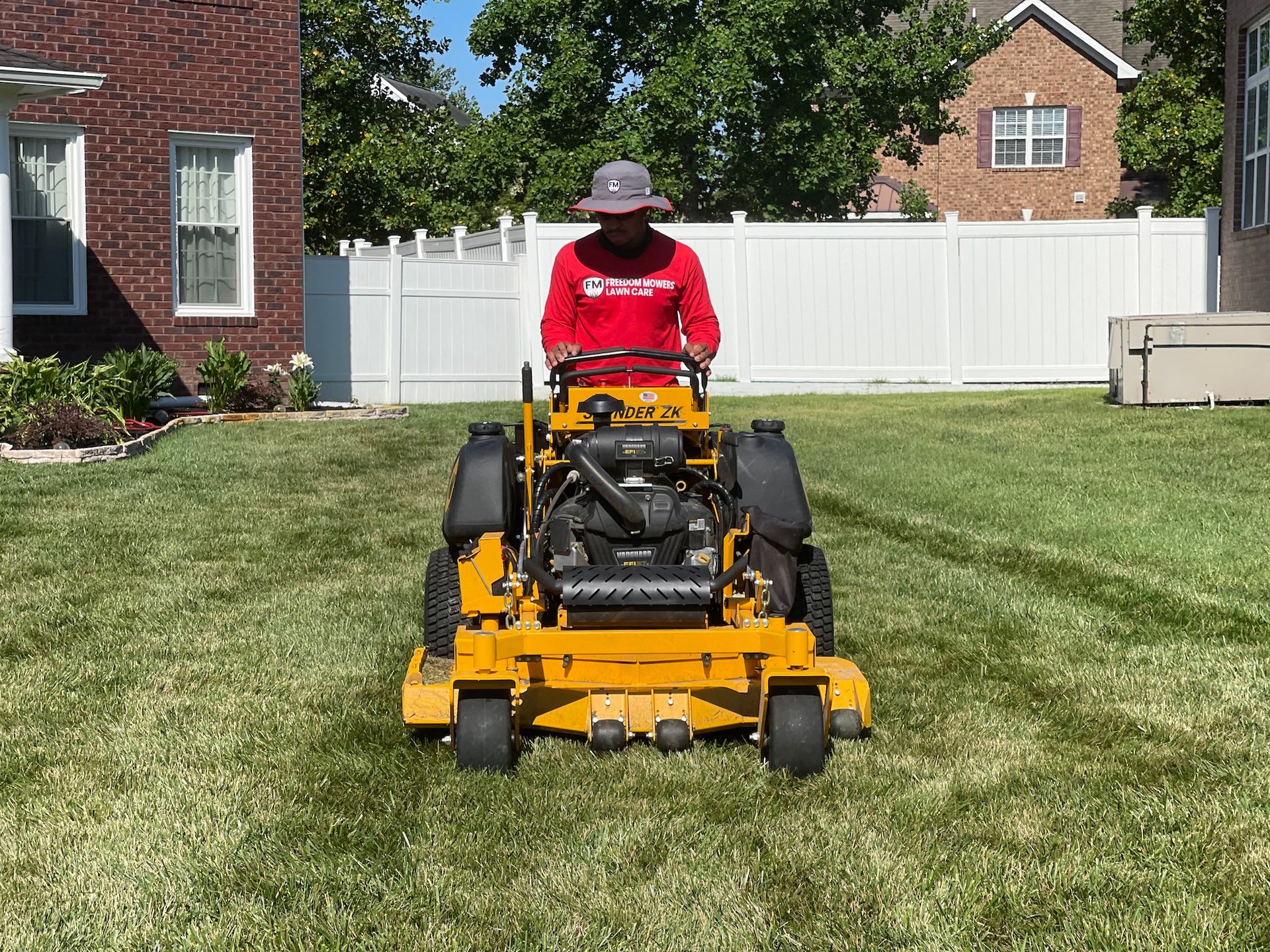 A man is riding a yellow lawn mower on a lush green lawn.