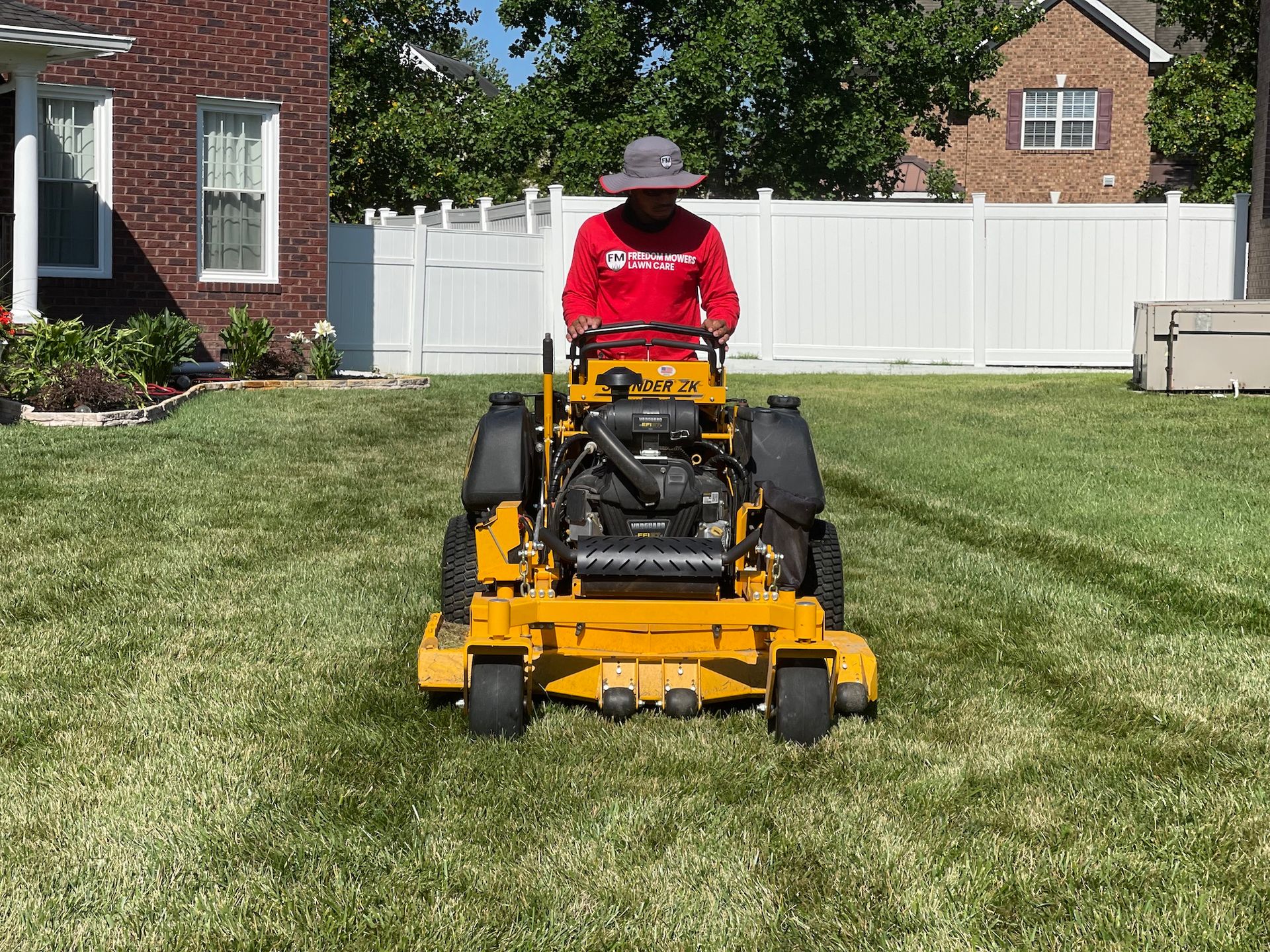 A man is riding a yellow lawn mower on a lush green lawn.
