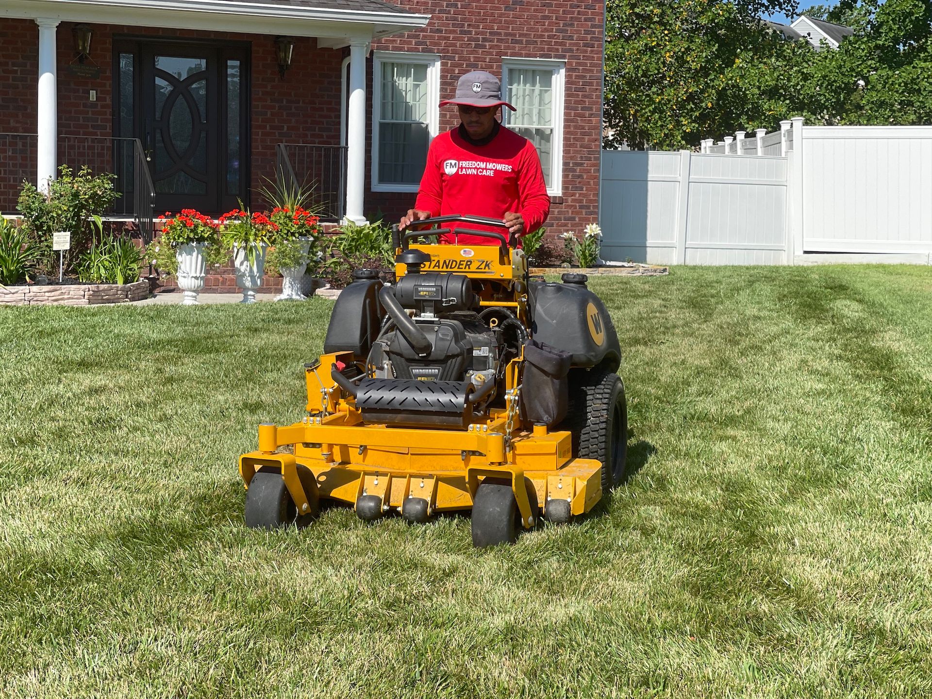 A man is riding a yellow lawn mower on a lush green lawn.