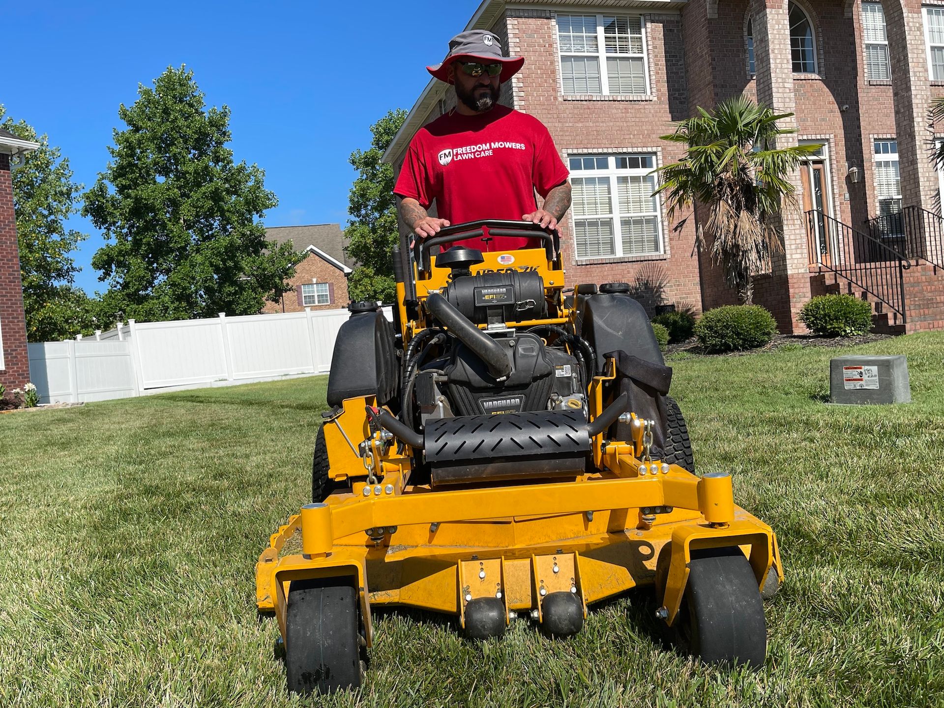 A man is riding a yellow lawn mower in front of a house.