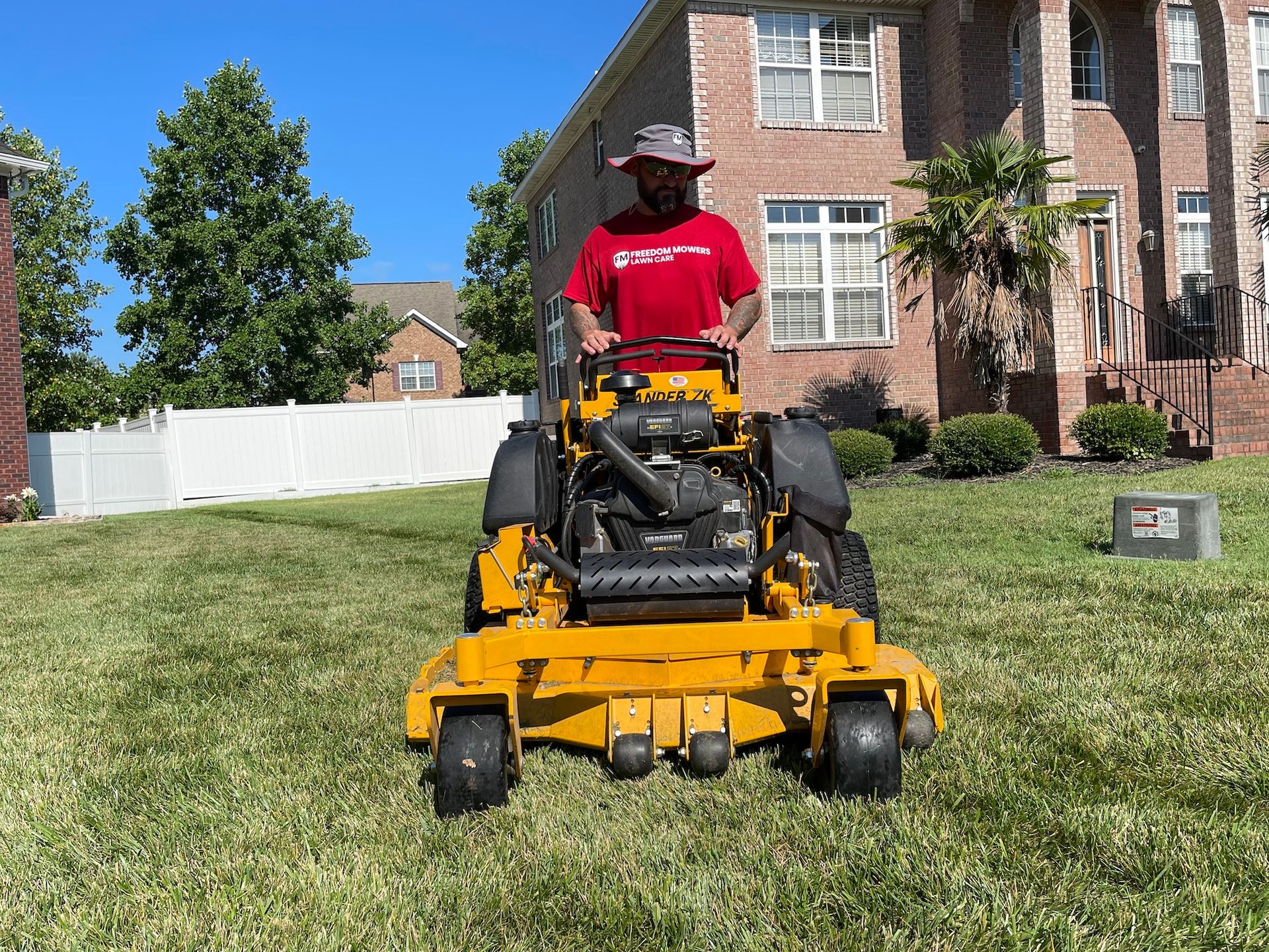 A man is riding a yellow lawn mower in front of a house.