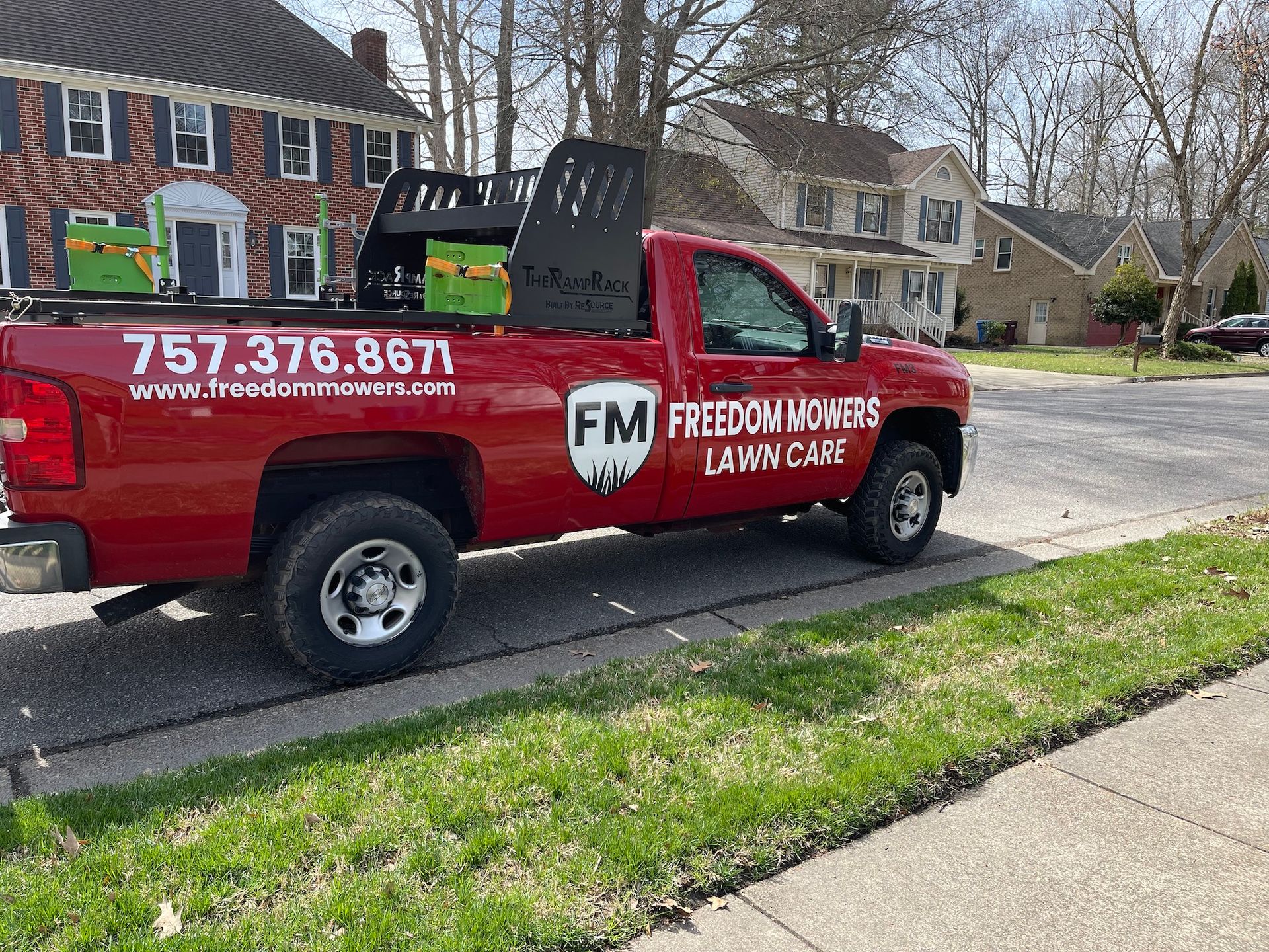 A red truck is parked on the side of the road in front of a house.