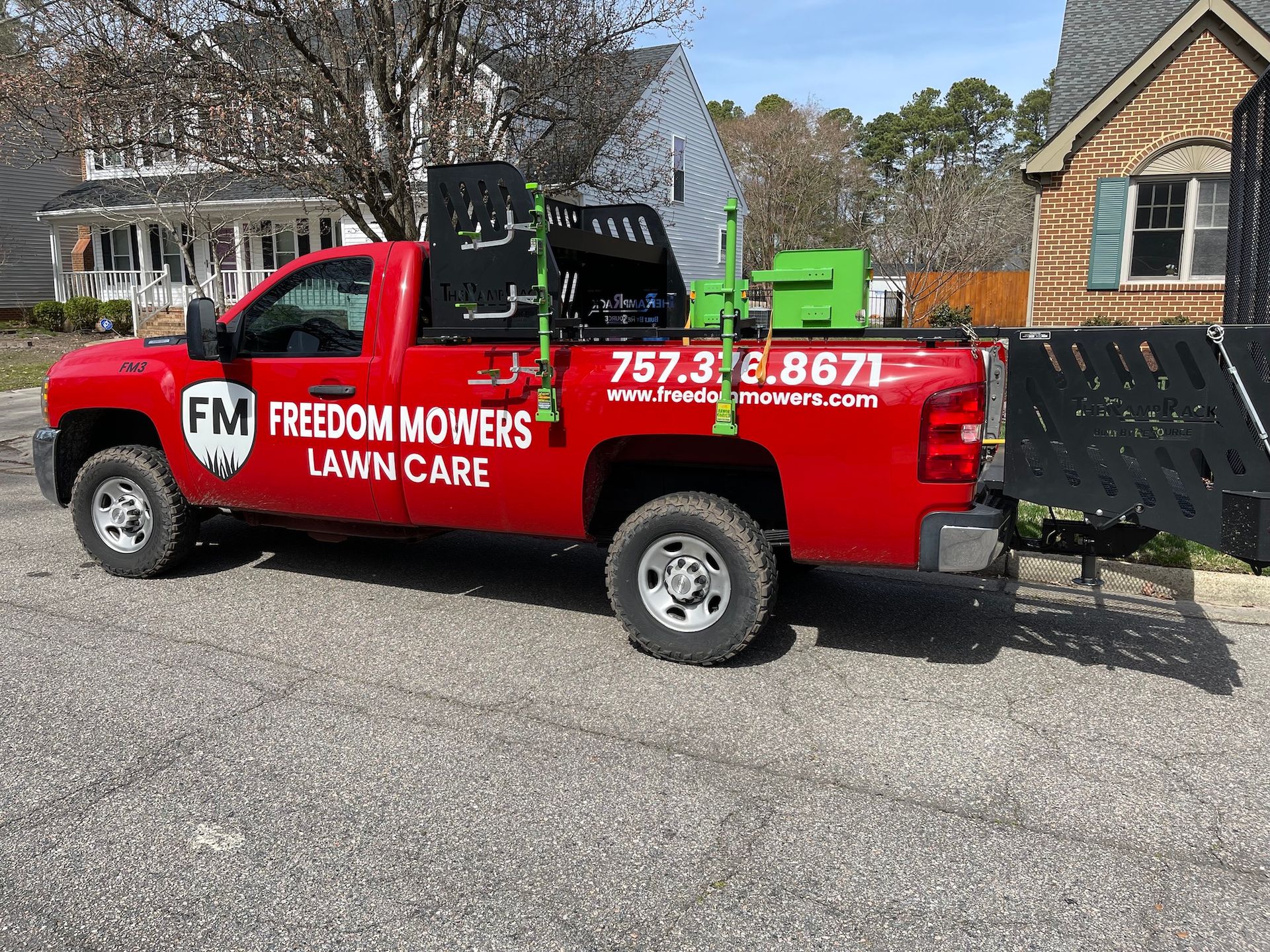 A red truck with a trailer attached to it is parked in front of a house.