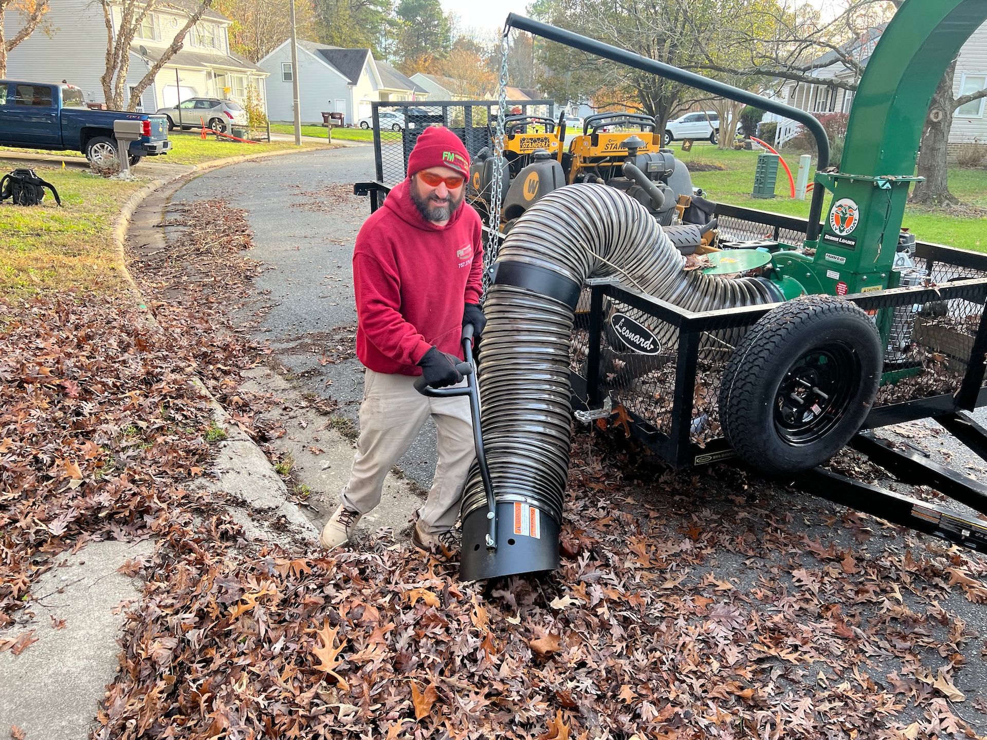A man is blowing leaves from a trailer with a hose.
