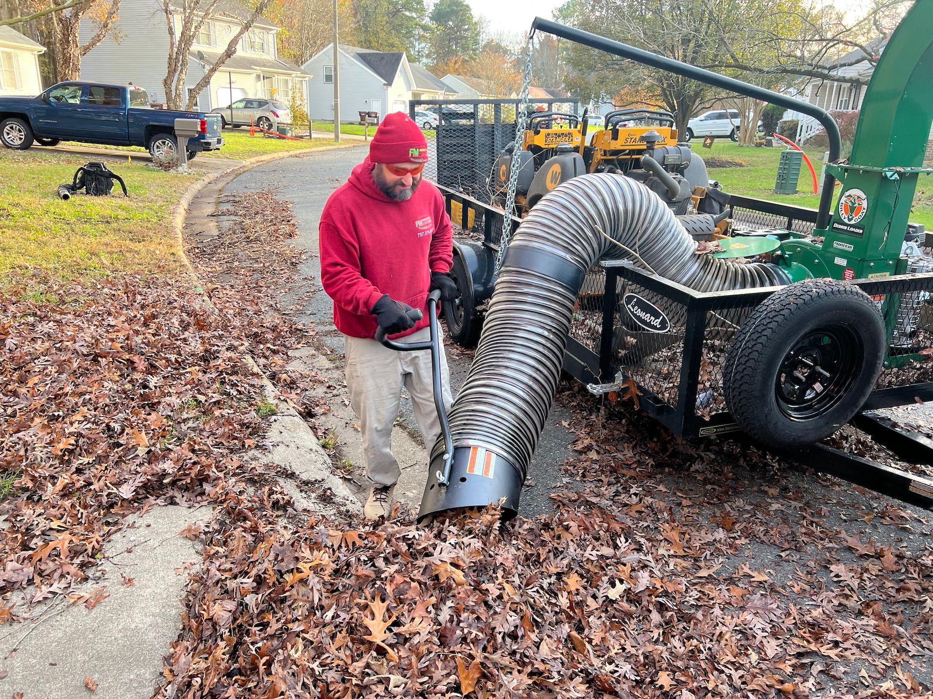 A man is blowing leaves from a trailer with a hose.