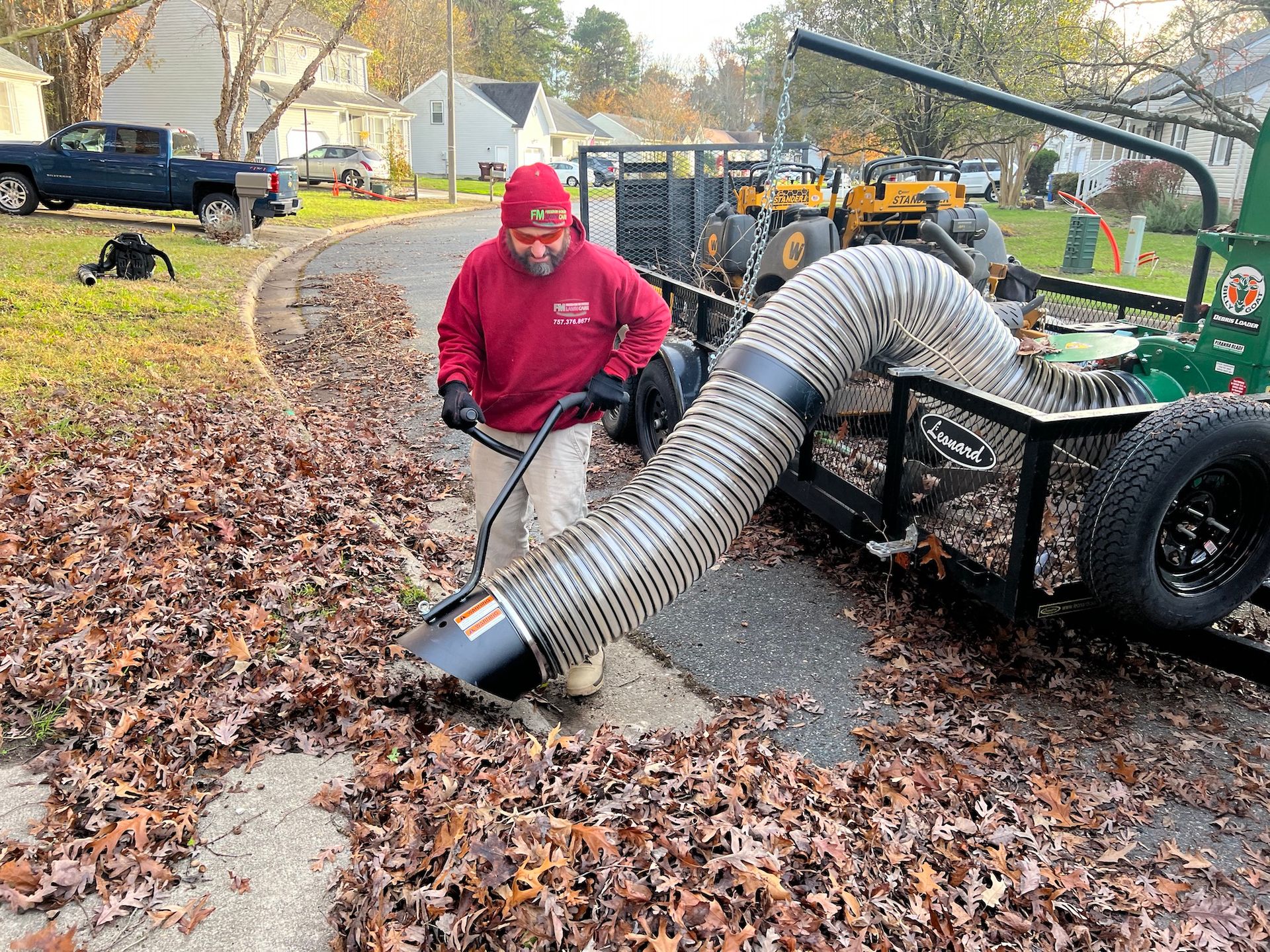 A man is blowing leaves from the ground with a hose.